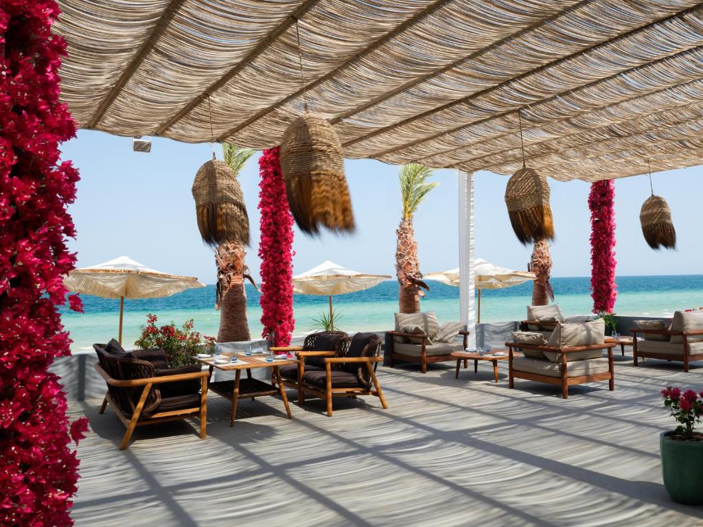 a patio at the beach with chairs and umbrellas at Ramlah Resort Qatar in Mesaieed