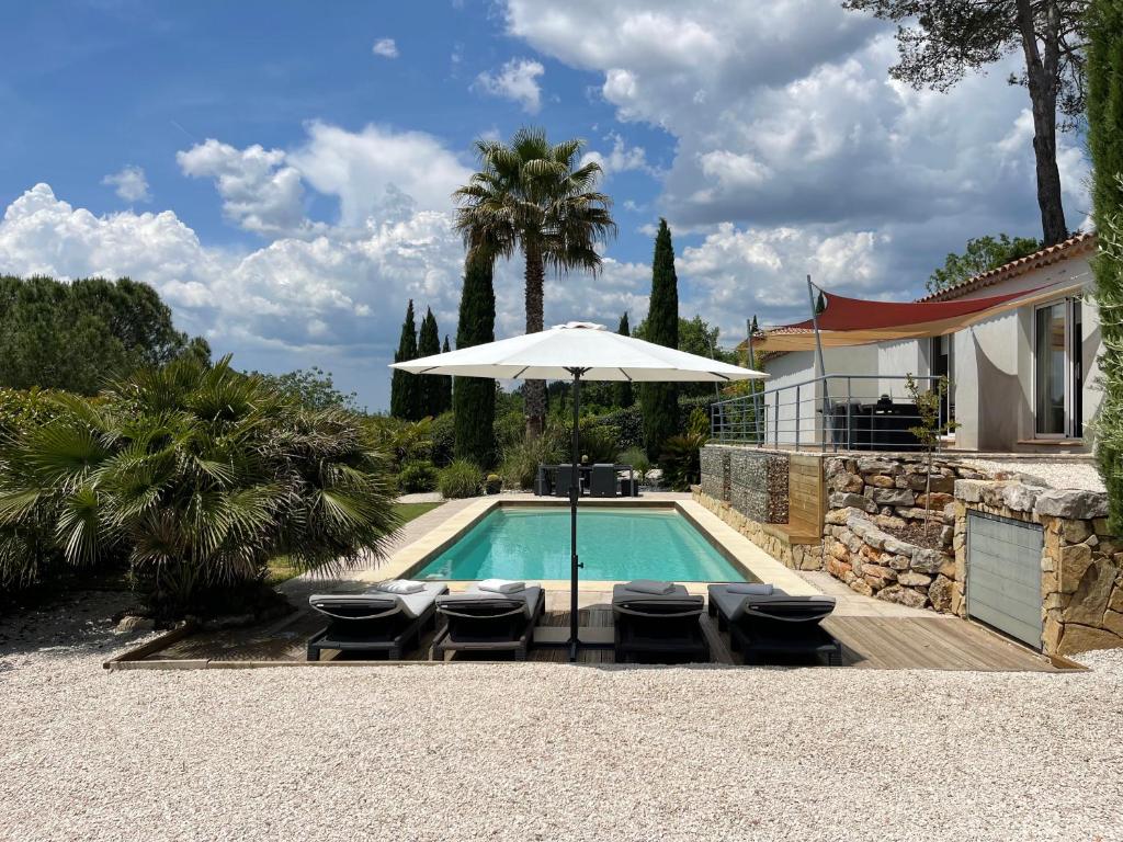 a swimming pool with chairs and an umbrella at Villa Grey - Brignoles - Provence verte in Brignoles