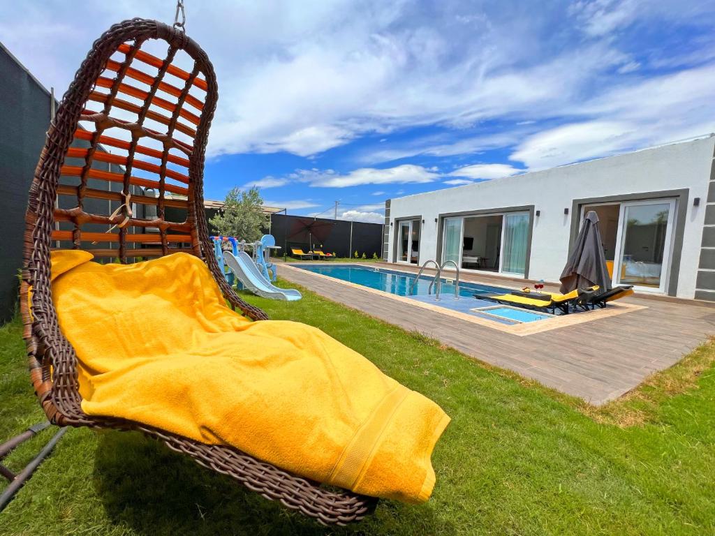 wiklinowe krzesło siedzące w trawie obok basenu w obiekcie Villa Ruya by Sakina Escapes w mieście Fethiye