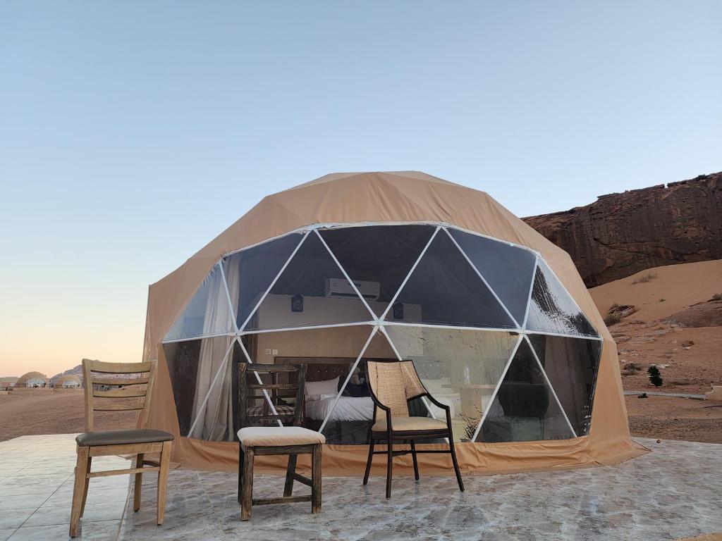 uma tenda no deserto com duas cadeiras e mesas em Family Camp em Wadi Rum