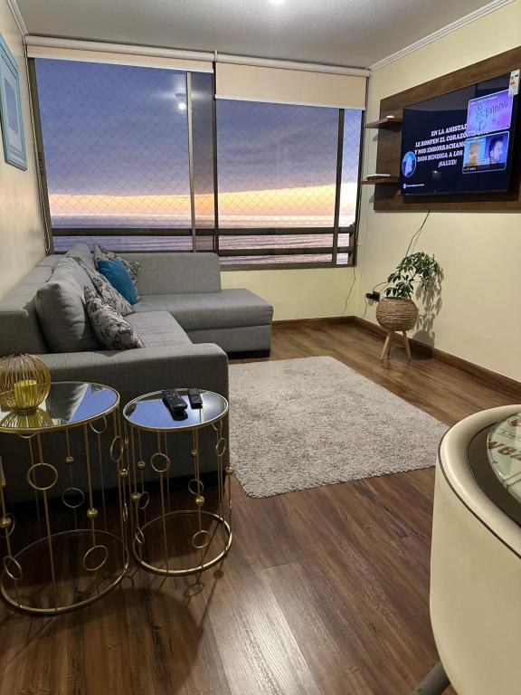 uma sala de estar com um sofá e uma televisão em Cómodo departamento sector sur Iquique em Iquique