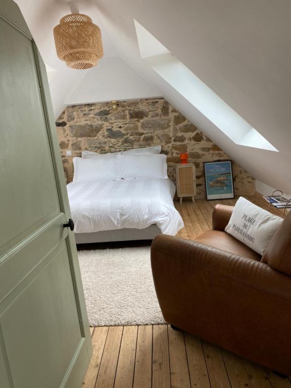 1 dormitorio con cama blanca y sofá en Les chambres de sainte barbe en Plougasnou