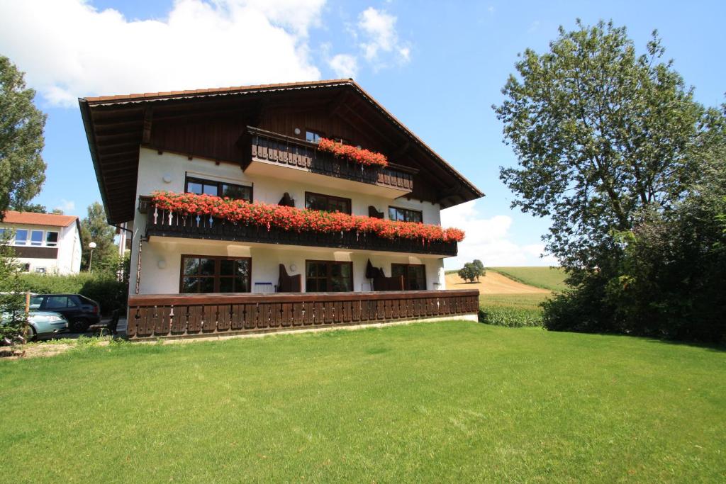 een huis met rode bloemen aan de zijkant bij Ferienwohnungen Kirschner in Bad Birnbach