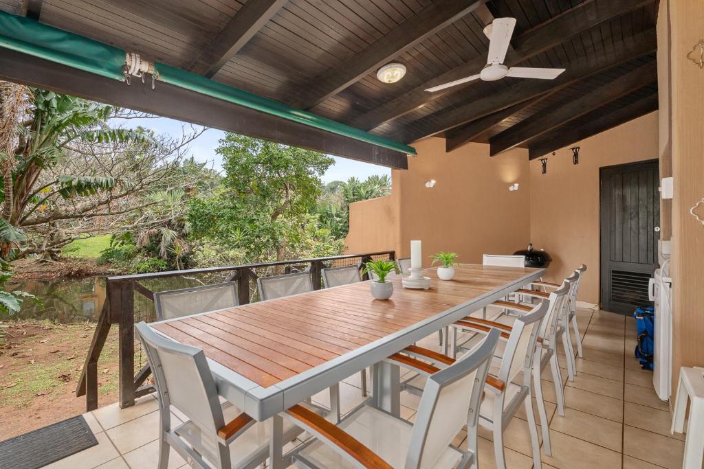 une salle à manger extérieure avec une table et des chaises en bois dans l'établissement San Lameer Villa 3503 - 4 Bedroom Standard- 8 pax - San Lameer Rental Agency, à Southbroom