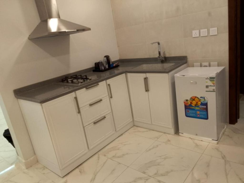 a kitchen with white cabinets and a refrigerator at سحاب in Yanbu