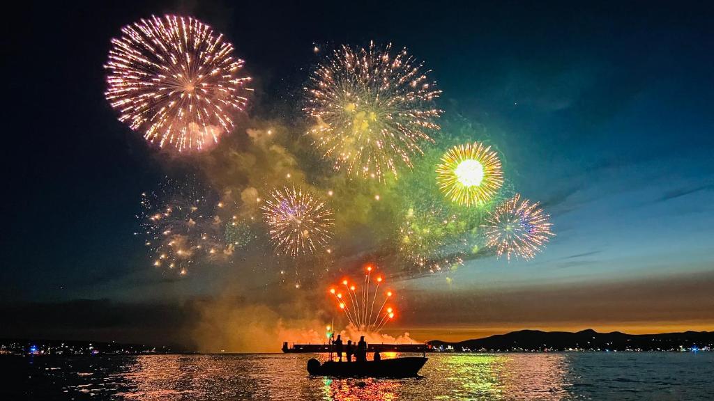 a group of people in a boat in the water with fireworks at AristocratHomeStay in Vancouver