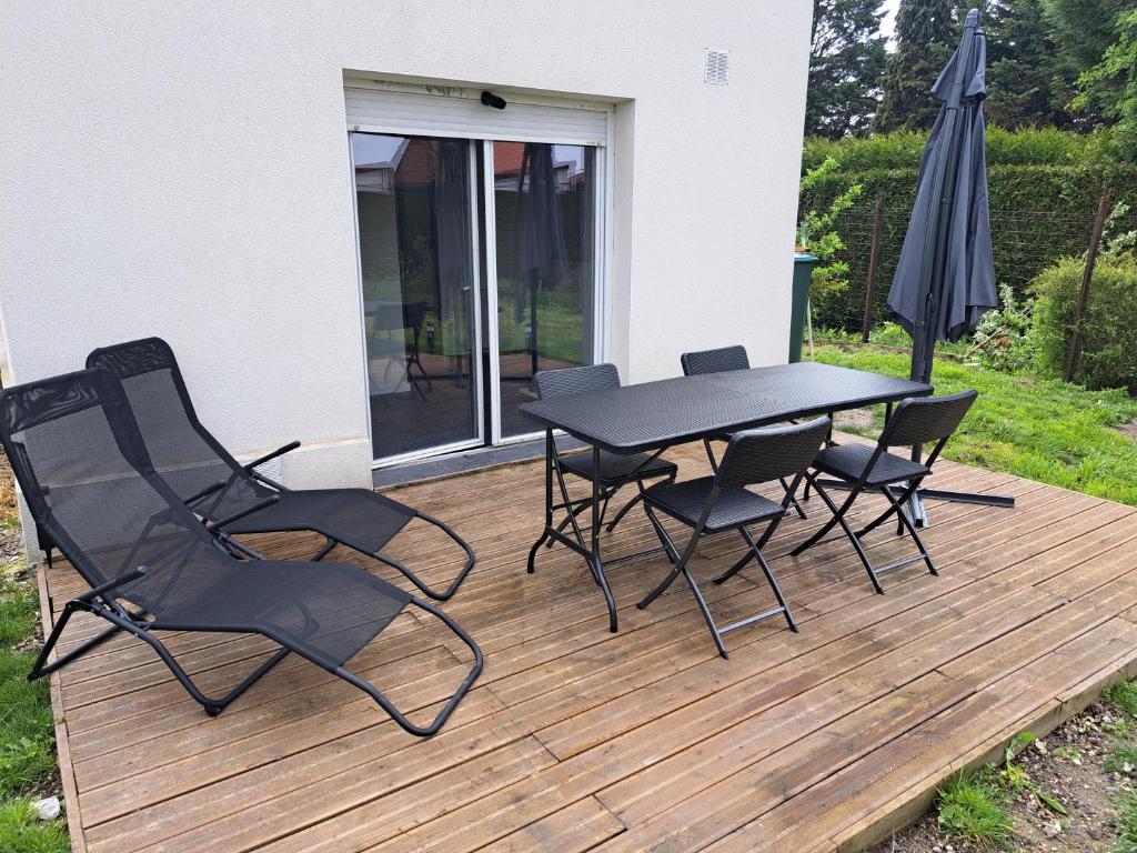 una mesa y sillas en una terraza de madera con sombrilla en La maison d isa en Lens