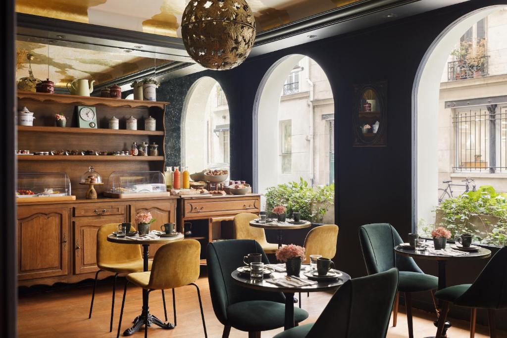 een restaurant met tafels en stoelen in een kamer met ramen bij Albert's Hotel in Parijs