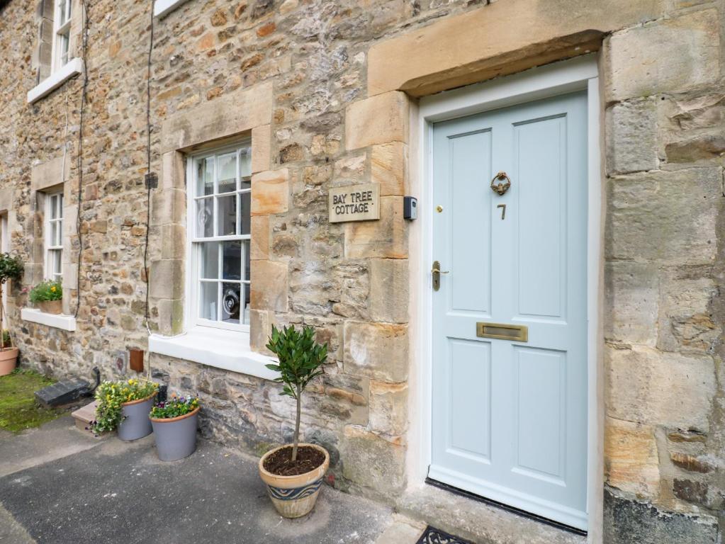 a white door of a stone building with potted plants at Bay Tree Cottage in Richmond