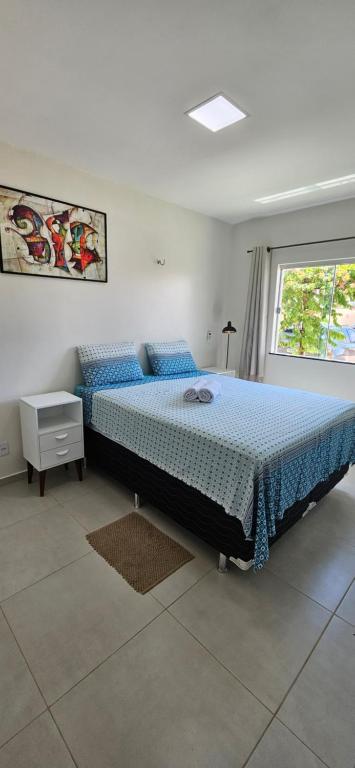 um quarto com uma cama grande com lençóis azuis e uma janela em Cantinho do Atalaia à 650 metros da praia - Seu conforto fora de casa em Salinópolis