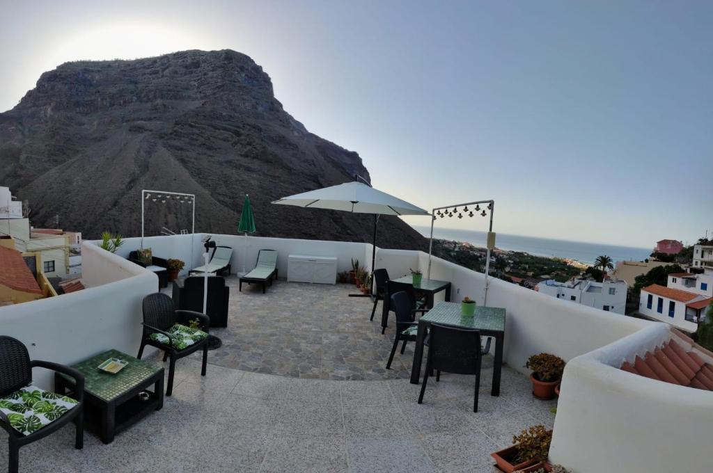 eine Terrasse mit Tischen, Stühlen und einem Berg in der Unterkunft Apartamentos Mussa in Valle Gran Rey