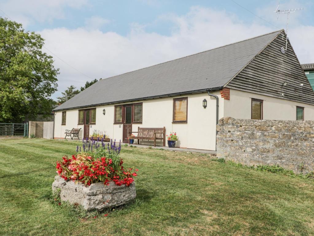 a white house with a stone wall and a yard at Roan Cottage in Lydiard Millicent