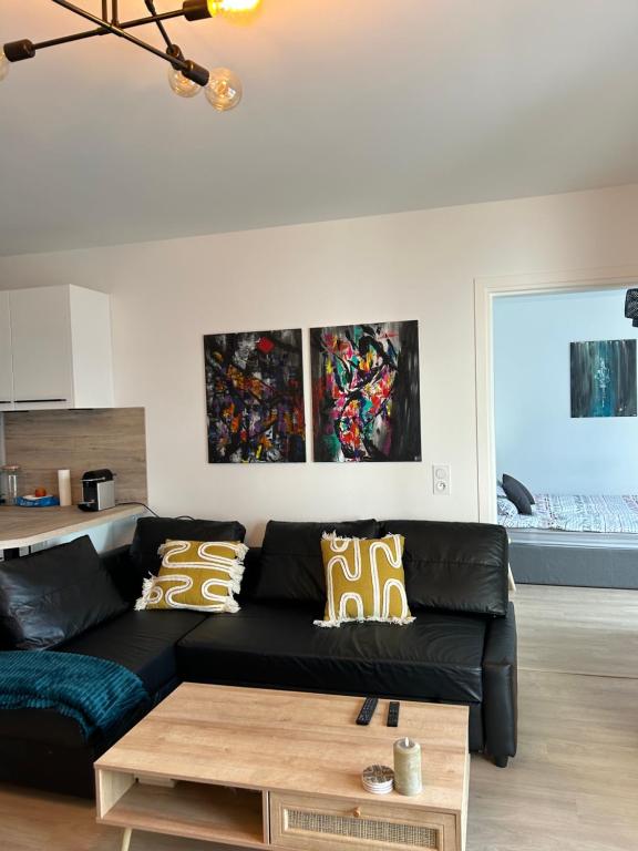 a living room with a black couch and a coffee table at Chic &amp; moderne appartement - proximité métro in Asnières-sur-Seine