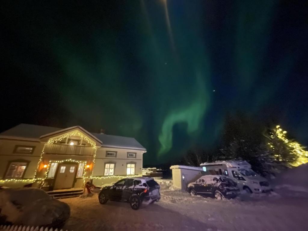 uma casa com carros estacionados na neve sob a aurora boreal em Brand New Studio Apartment in Tromso - hotspot em Tromsø