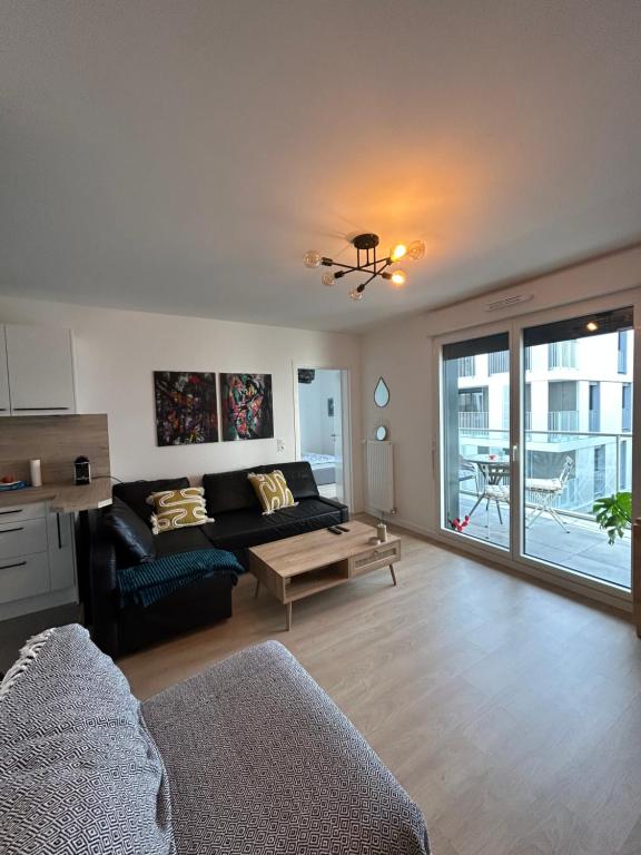 a living room with a couch and a table at Chic &amp; moderne appartement - proximité métro in Asnières-sur-Seine