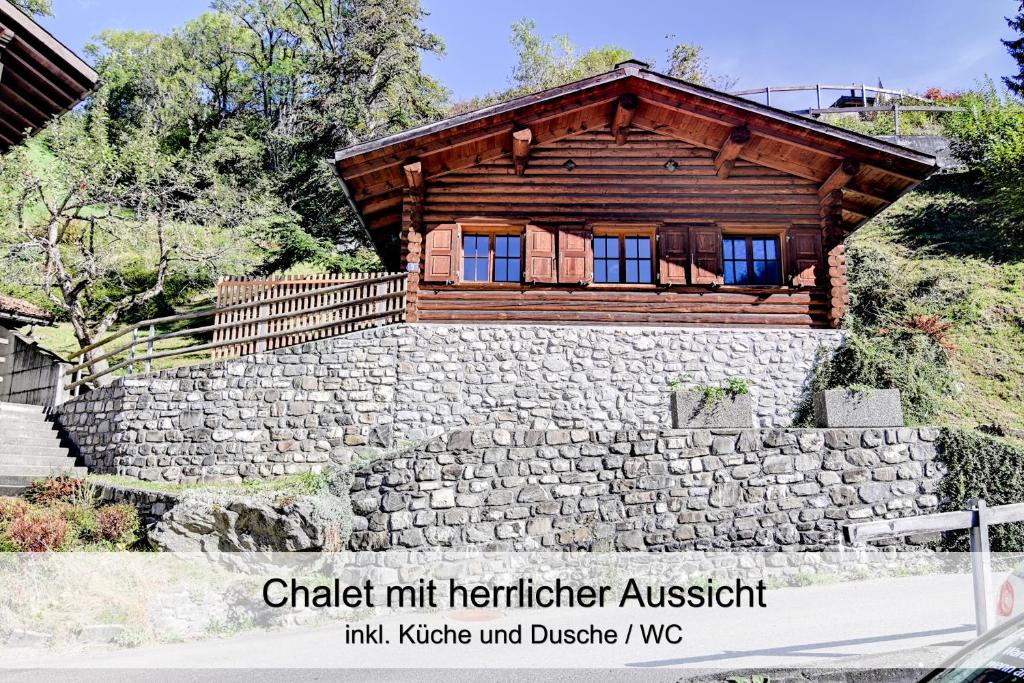 una pequeña cabaña de madera en una pared de piedra en Gemütliches Chalet mit schöner Aussicht, en Küblis