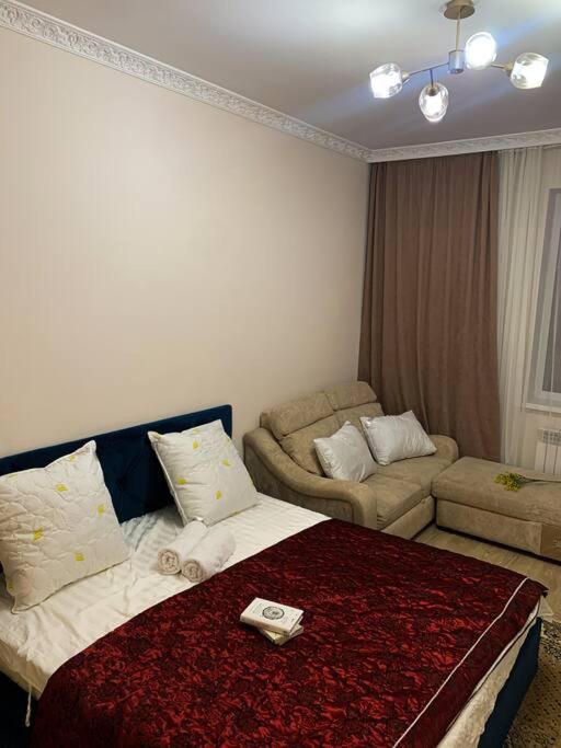um quarto de hotel com uma cama e um sofá em 1-комнатная квартира посуточно em Taldykolʼ