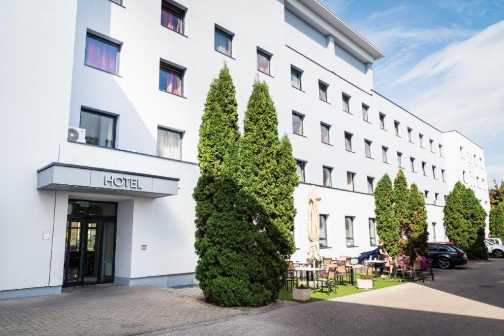 duży biały budynek z drzewami przed nim w obiekcie Hotel Famulus w Győr