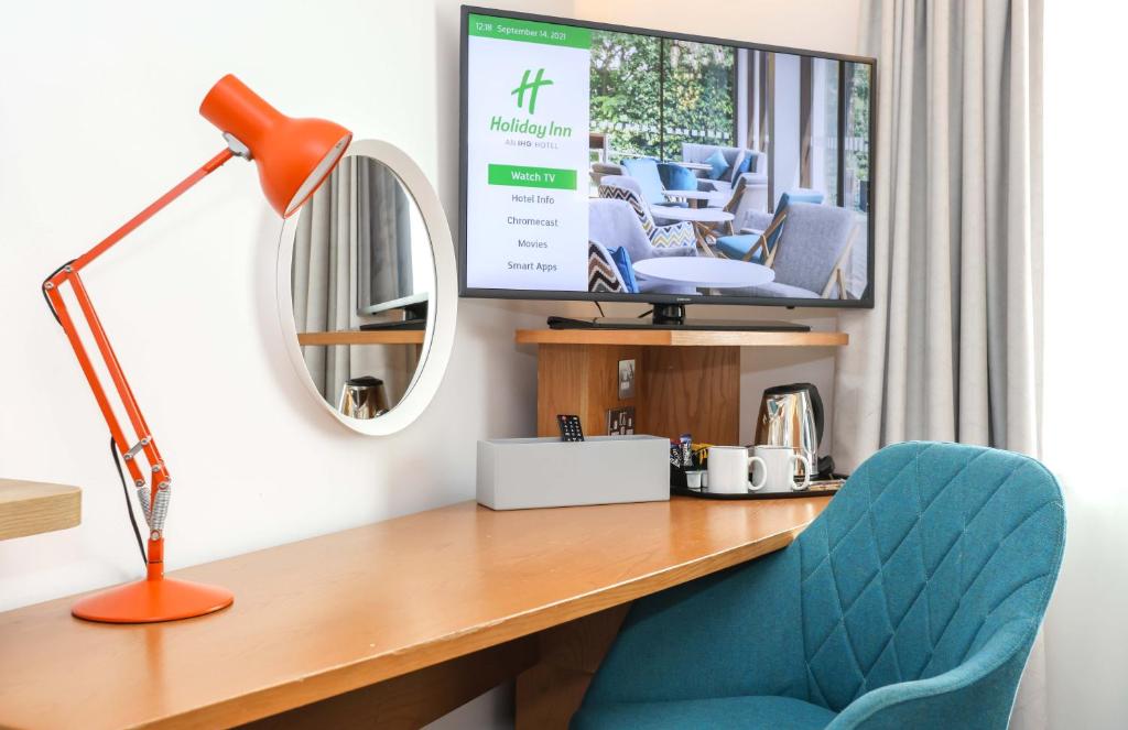 a desk with a chair and a lamp and a mirror at Holiday Inn Bournemouth by IHG in Bournemouth