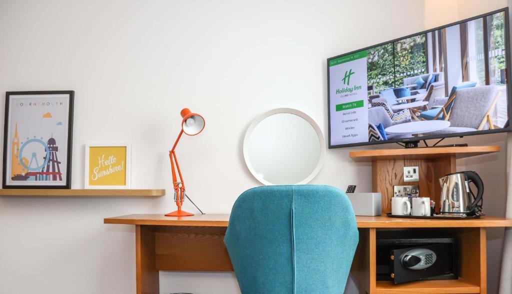 a desk with a blue chair and a mirror at Holiday Inn Bournemouth by IHG in Bournemouth