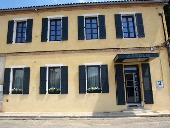 un bâtiment avec des fenêtres à volets noirs et une porte dans l'établissement Hôtel Absolu, à Castelsarrasin