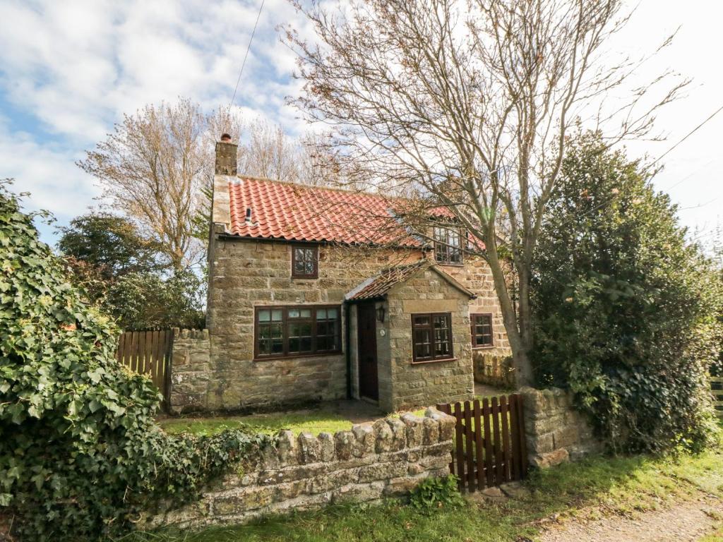 an old stone house with a fence at Holly Cottage in Whitby
