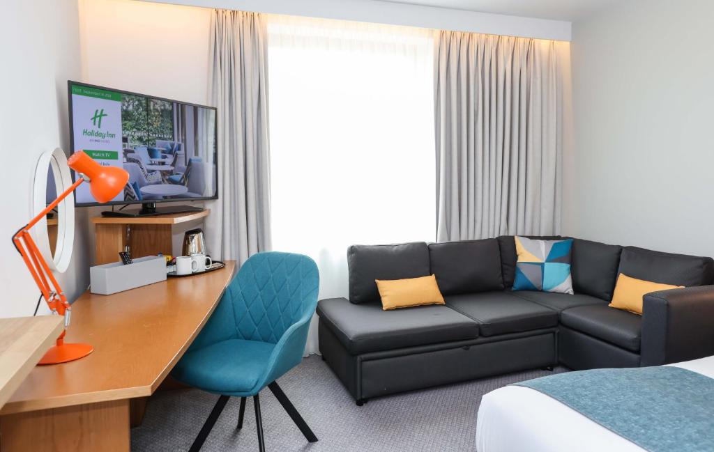 a hotel room with a couch and a desk and a bed at Holiday Inn Bournemouth by IHG in Bournemouth