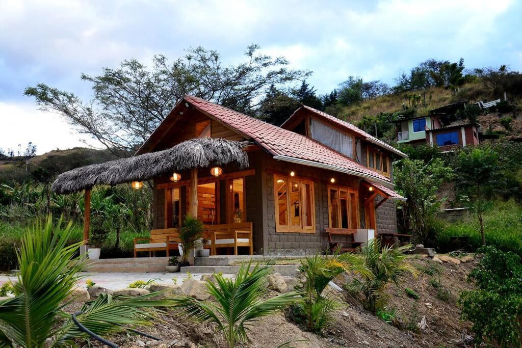 ein kleines Holzhaus mit einer Bank davor in der Unterkunft Casa Kambana en Vilcabamba in Loja