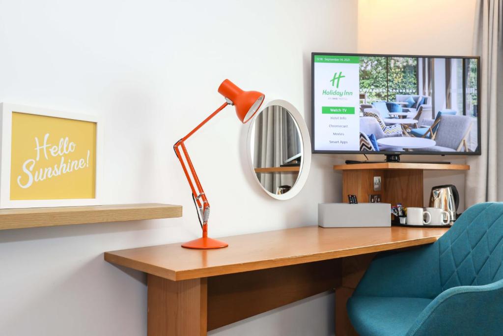 a desk with a lamp and a blue chair at Holiday Inn Bournemouth by IHG in Bournemouth