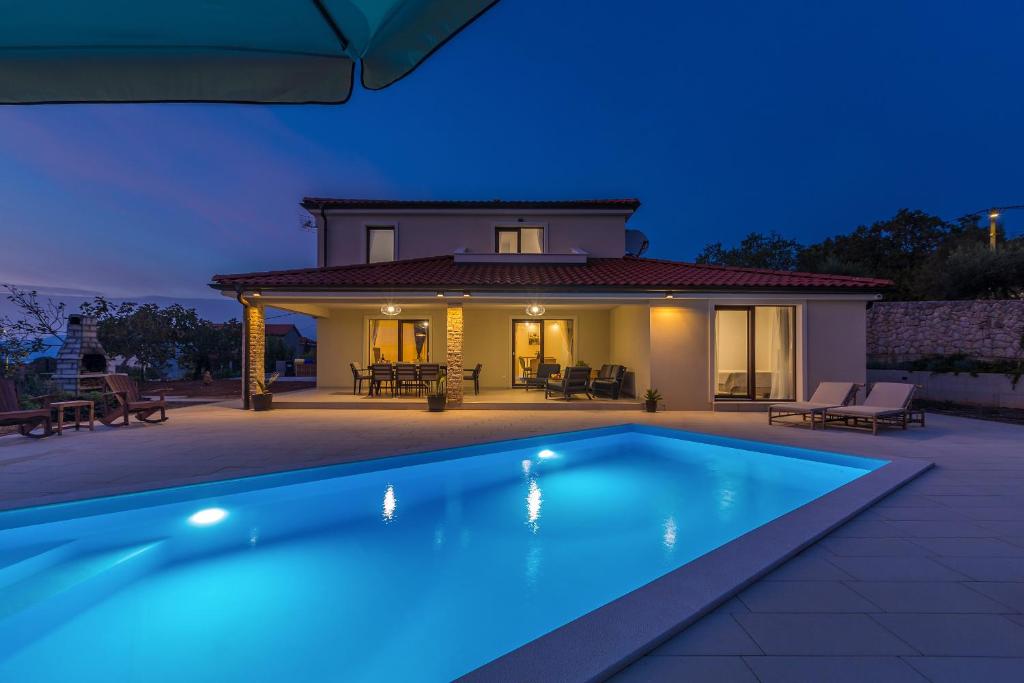 a swimming pool in front of a house at night at Holiday house LUNA in Bajčići