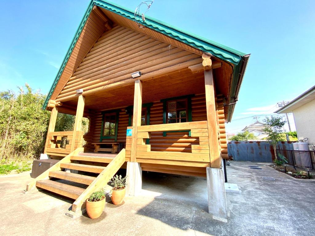 a small log cabin with a porch and stairs at on a journey 千葉 九十九里 in Kujukuri