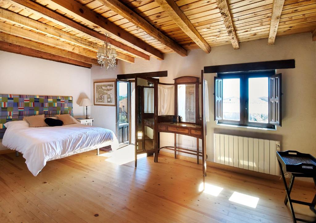 a bedroom with a bed and a table and windows at HESTIA VuT in Ayllón
