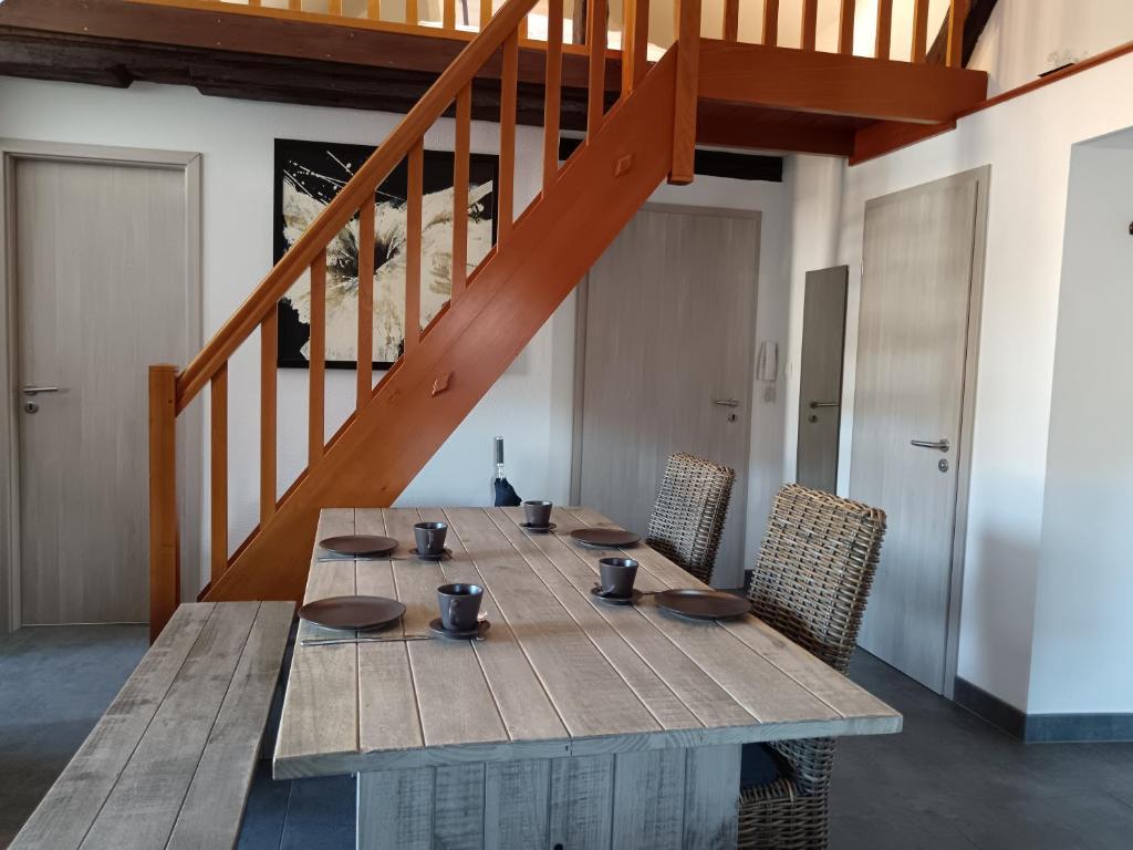 une table en bois avec des chaises et un escalier en bois dans l'établissement Le Bretzel, à Ribeauvillé