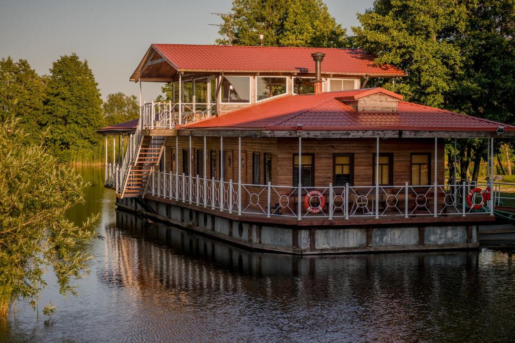 a house on a boat in the water at Mėlynojo karpio barža in Kintai