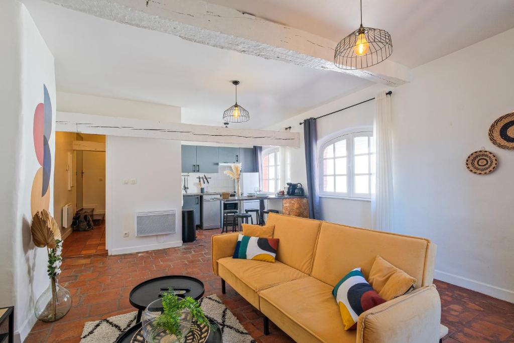 a living room with a couch and a kitchen at Numéro 6 - Place Nationale - Wifi et Fibre in Montauban