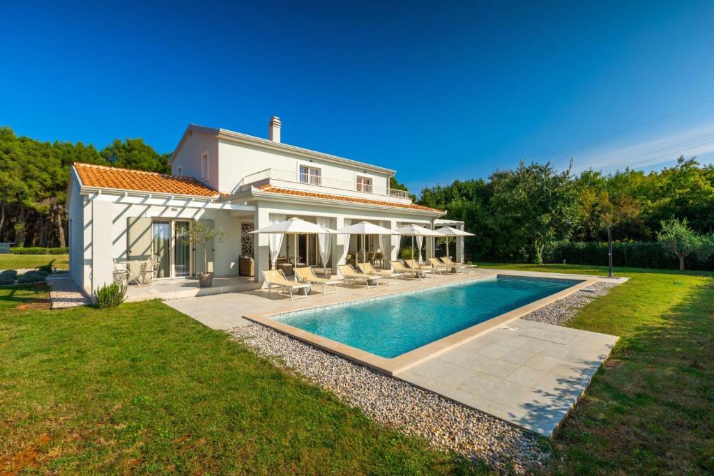 a house with a swimming pool in the yard at Modern villa Oliveti with pool and grill in Porec in Frata
