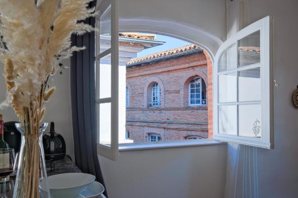 a window in a room with a brick building at Numéro 6 - Place Nationale - Wifi et Fibre in Montauban