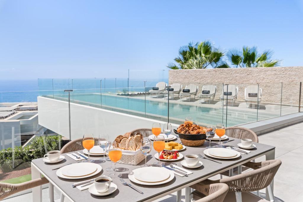 a table with food on a balcony with a view of the ocean at Karat Villa Zambrano in Guía de Isora