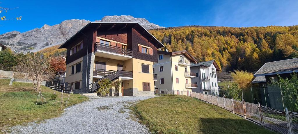 ein Haus auf einem Hügel mit einem Berg im Hintergrund in der Unterkunft Appartamento con splendida vista su pista Stelvio in Bormio