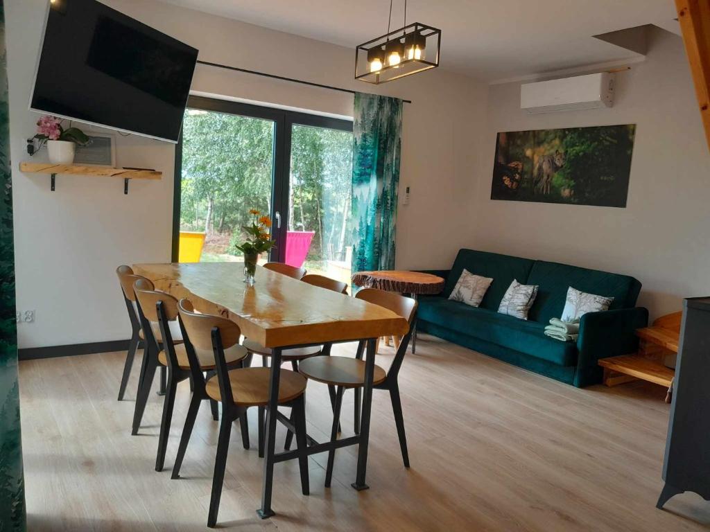 ein Wohnzimmer mit einem Tisch, Stühlen und einem Sofa in der Unterkunft Przystanek Las in Gąsawa