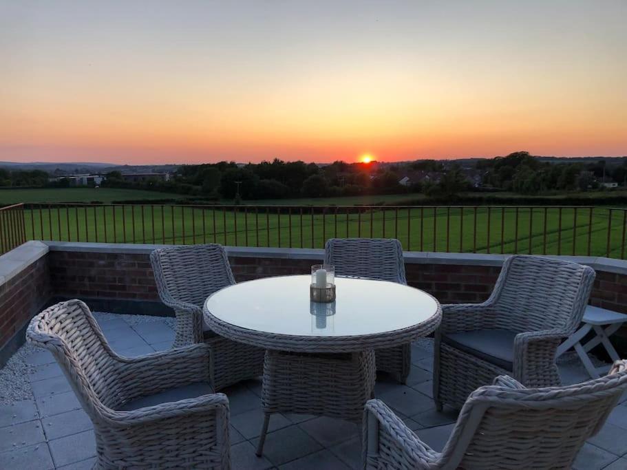 a patio with a table and chairs at sunset at 2 Bedroom cottage with Beautiful views over the Mendips in Radstock