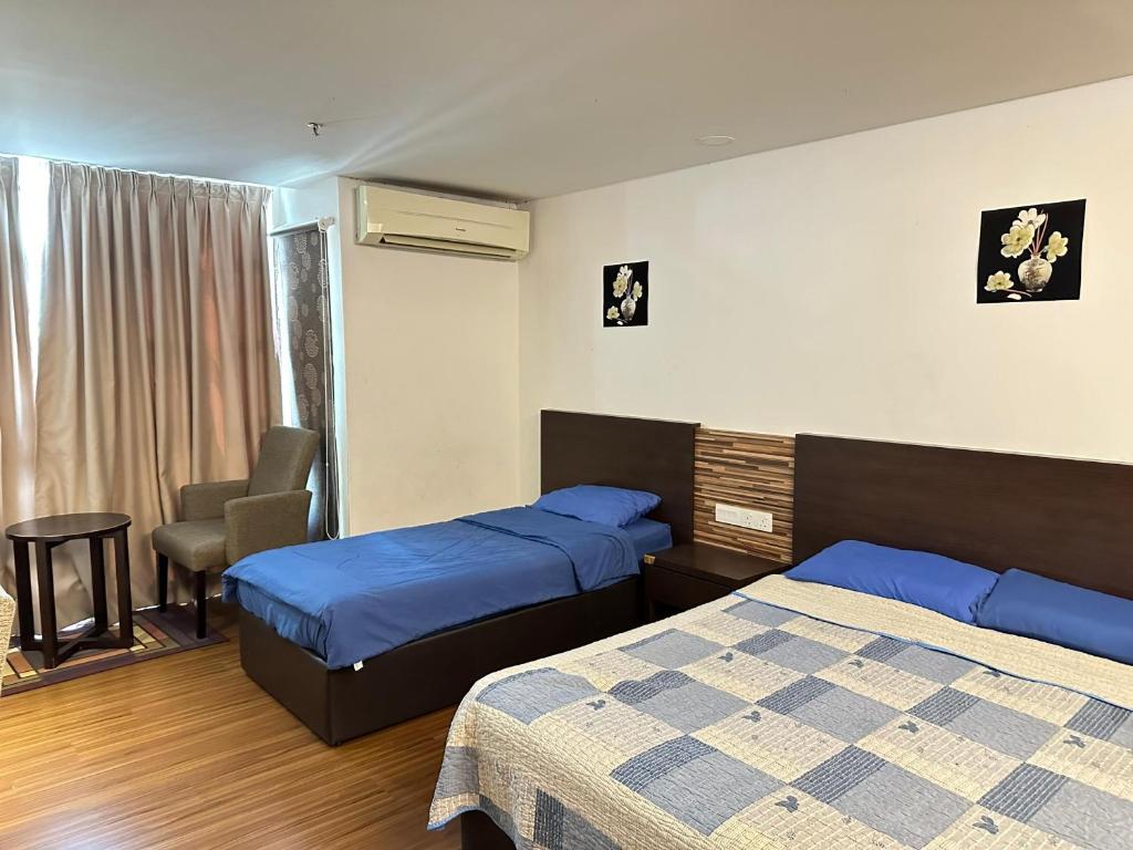 a hotel room with two beds and a chair at Nazrins Studio Apartment KBCP in Kota Bharu