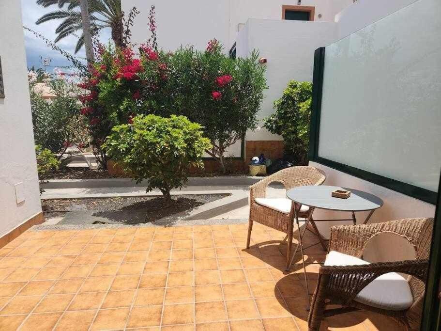 a patio with a table and chairs and flowers at Happy House Puerta del Sol in Caleta De Fuste
