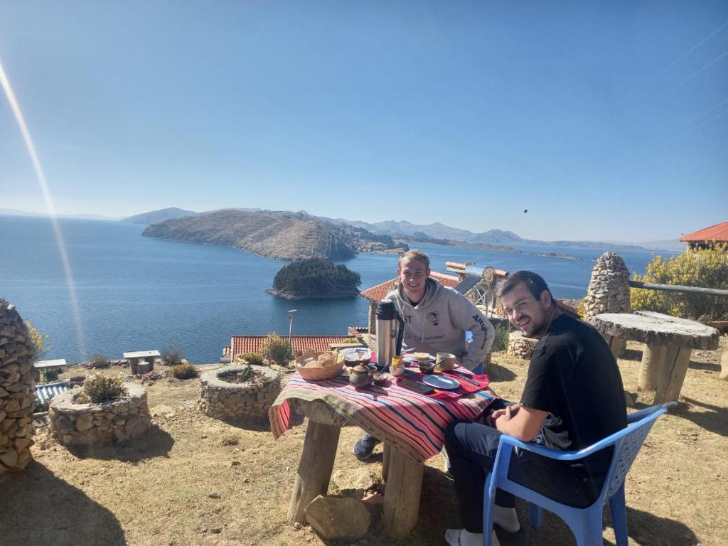 two men sitting at a picnic table with a view of the ocean at Refugio Ecologico Kalluchi in Comunidad Yumani