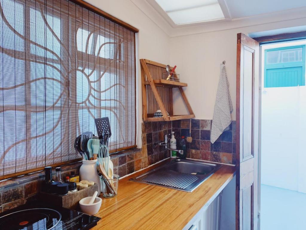 una cucina con bancone e lavandino e una finestra di Cottage On Windsor a Città del Capo