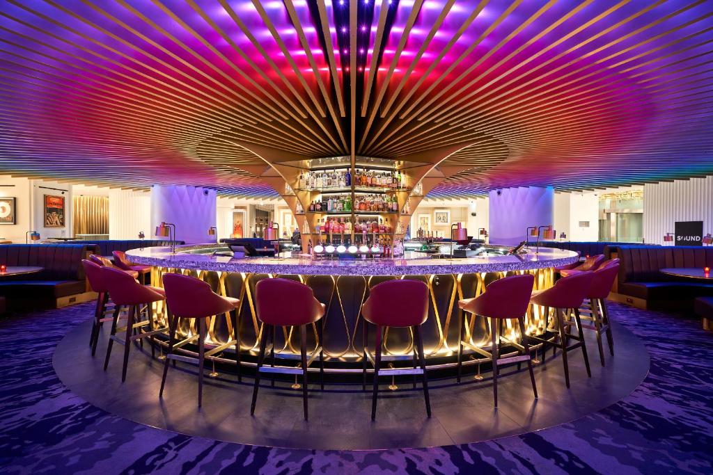 a bar with red chairs and purple lighting at The Cumberland, London in London