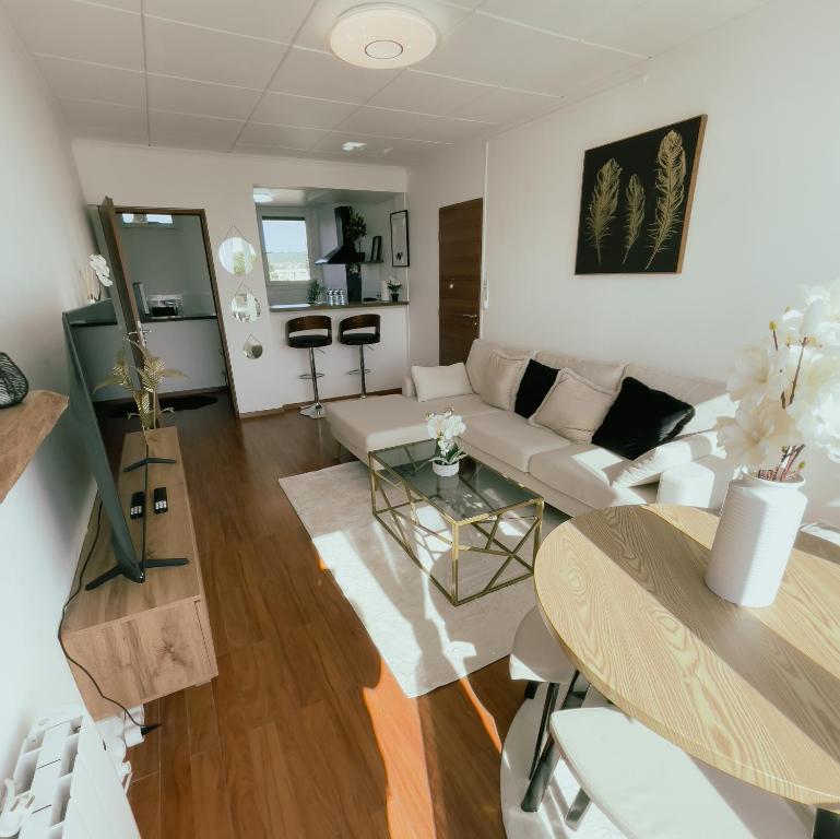 uma sala de estar com um sofá branco e uma mesa em Appartement Cosy & Connecté à 15 min de Paris em Soisy-sous-Montmorency
