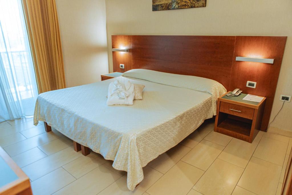 a bedroom with a large bed with a wooden headboard at Hotel Amico in Citta' Sant'Angelo