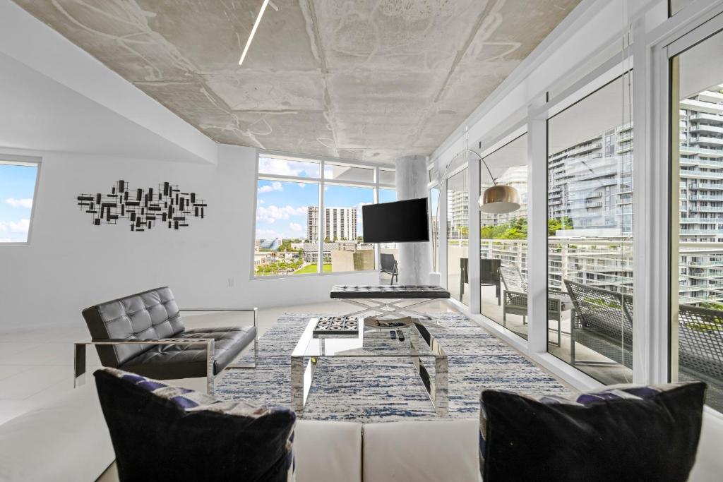 a living room with a tv and a couch and chairs at Spacious 3-Bedroom Midtown Condo in Miami