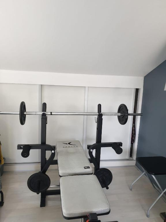 a room with a gym with a bench and weights at Villa JO 2024 in Buc
